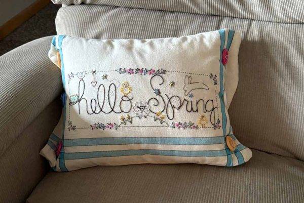 "Hello Spring" seasonal home decor accent pillow on a chair