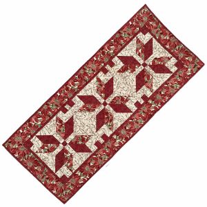 Cotton table runner with a design of red and green poinsettias accented with silver metallic thread on a light background.