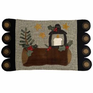 Wool mat featuring a brown Yule log decorated with green holly and red berries, an antique black street lamp with a white candle, and gold stars on a textured light brown background.