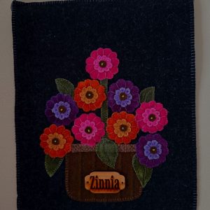 Zinnias Wool Hanging red, blue, purple and orange zinnias in a brown basket with green leaves