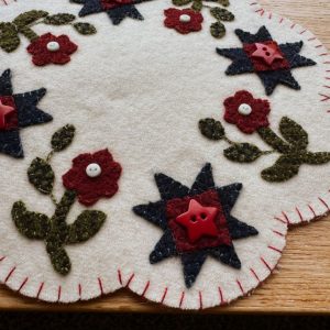 Red, White & Blooms Candle Mat, white background with green stems and leaves red flowers with white buttons blue stars with red star buttons