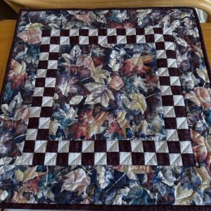 Blowing Leaves Table Topper fall colored leaves with blues, yellows, oranges, reds and purples quilted together