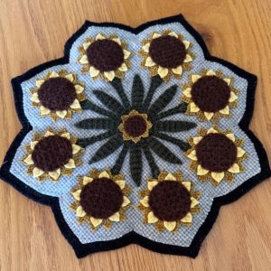 Sunflower Blossoms Wool Mat white and green checked fabric outlined in black with yellow and brown stitched sunflowers and green stems