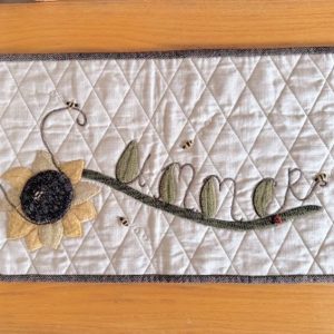 Summer Wall Quilt tan background with a yellow sunflower green leaves spelling out summer with yellow and black bumble bees flying around